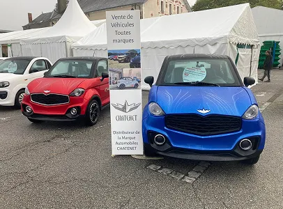 Deux voitures compactes, rouge et bleue, garées devant des tentes avec une bannière Chatenet à Azay-sur-Thouet dans les Deux-Sèvres 79