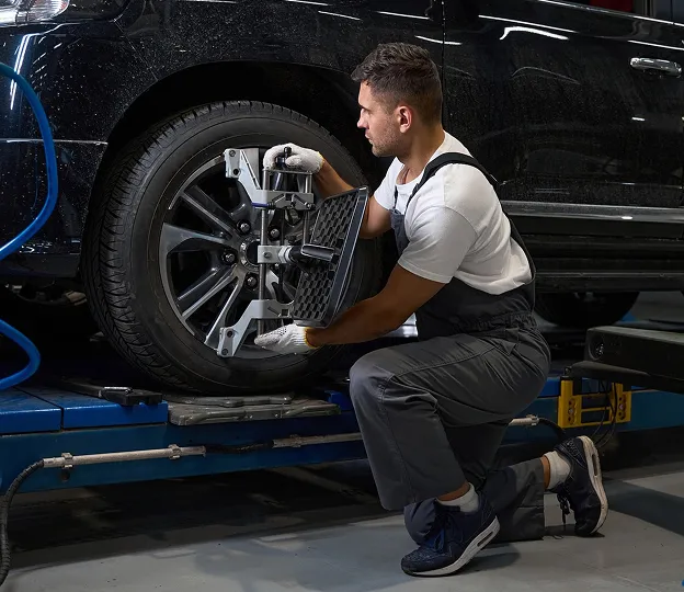 Mécanicien effectuant un alignement de roue sur une voiture noire dans un garage à Azay-sur-Thouet dans les Deux-Sèvres 79
