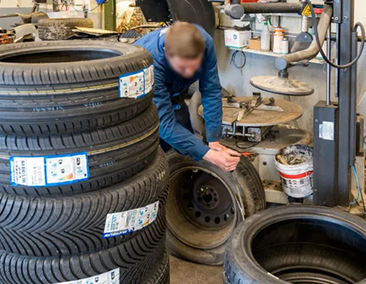 Mécanicien de pneus dans un garage, des pneus neufs empilés et une machine à Azay-sur-Thouet dans les Deux-Sèvres 79