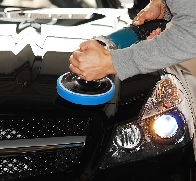 Personne polissant le capot noir brillant d'une voiture avec une machine à Azay-sur-Thouet dans les Deux-Sèvres 79